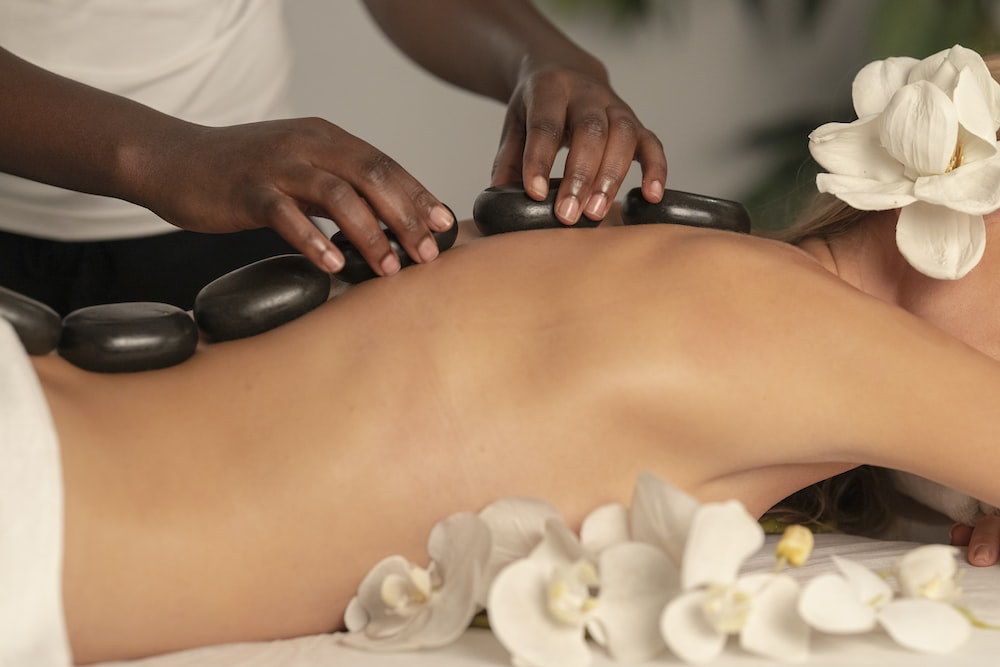 Person giving massage with pebbles to a customer